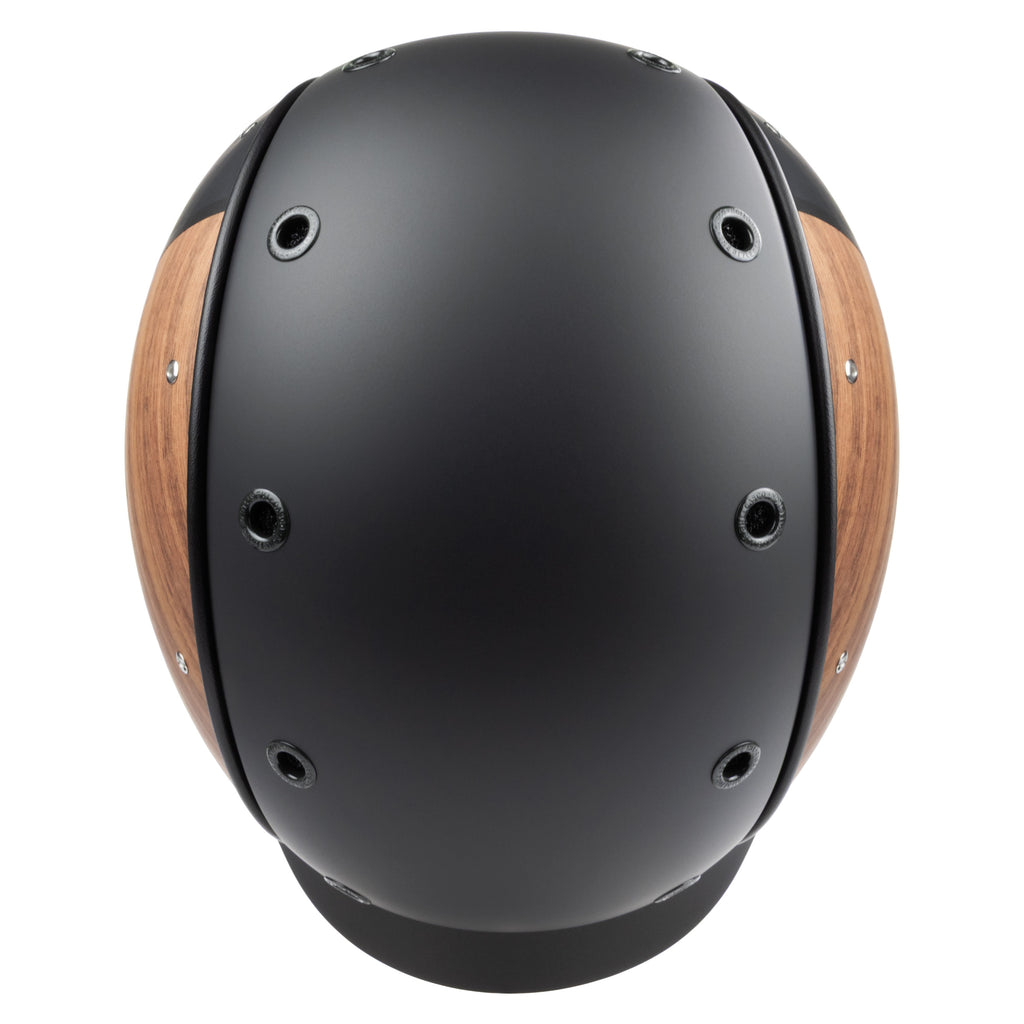 A matte black equestrian riding Casco helmet with natural wood-look panels on the sides, featuring a black chin strap, top view against white background