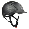 A CASCO matte black equestrian helmet with a subtle repeating logo pattern on the side panels, a matching black visor, and black chin straps with an orange release buckle, shown on a solid white background.