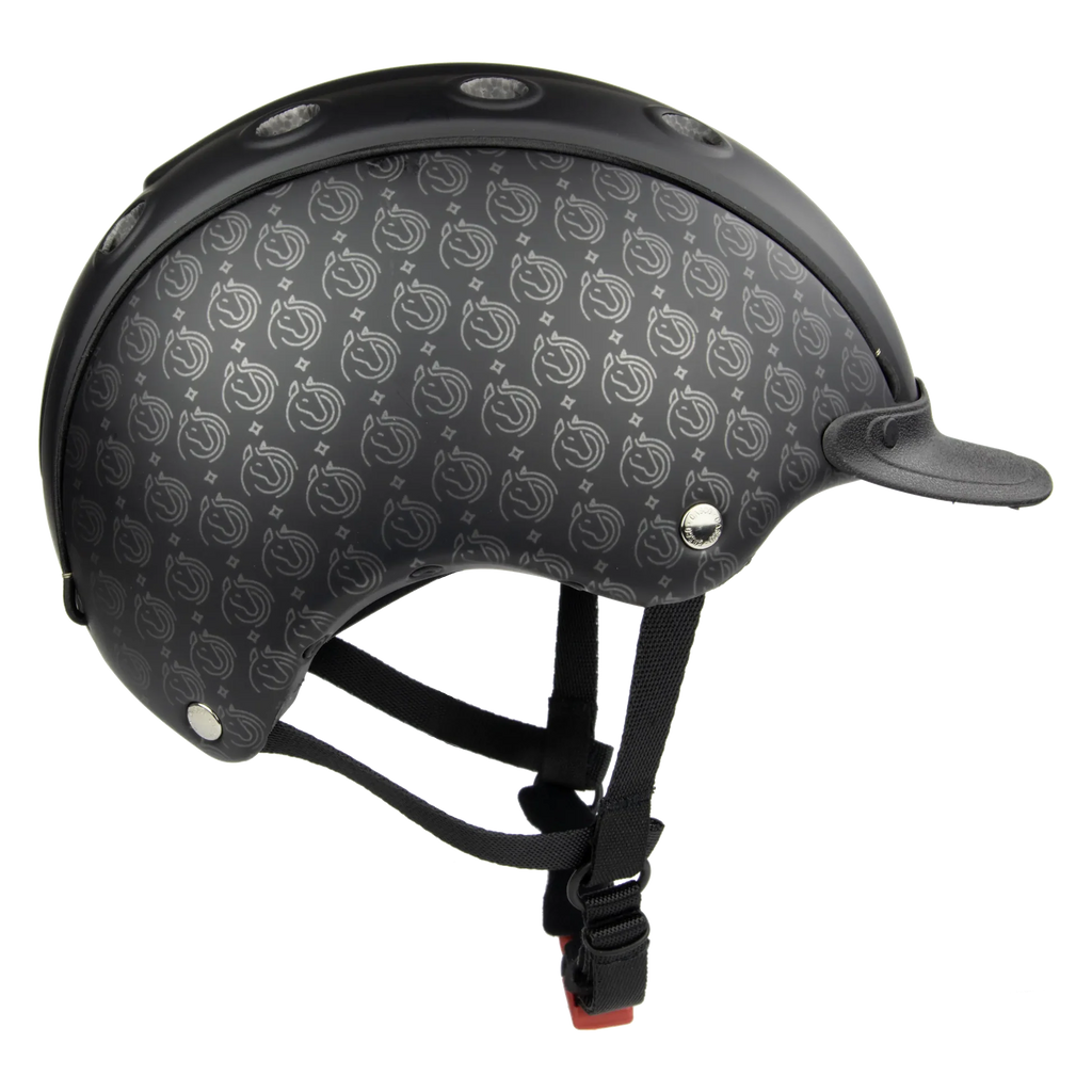 A black full-face CASCO helmet with a subtle repeating silver logo pattern, featuring a matching black visor and black chin straps with a red-and-black buckle, shown against a plain white background.