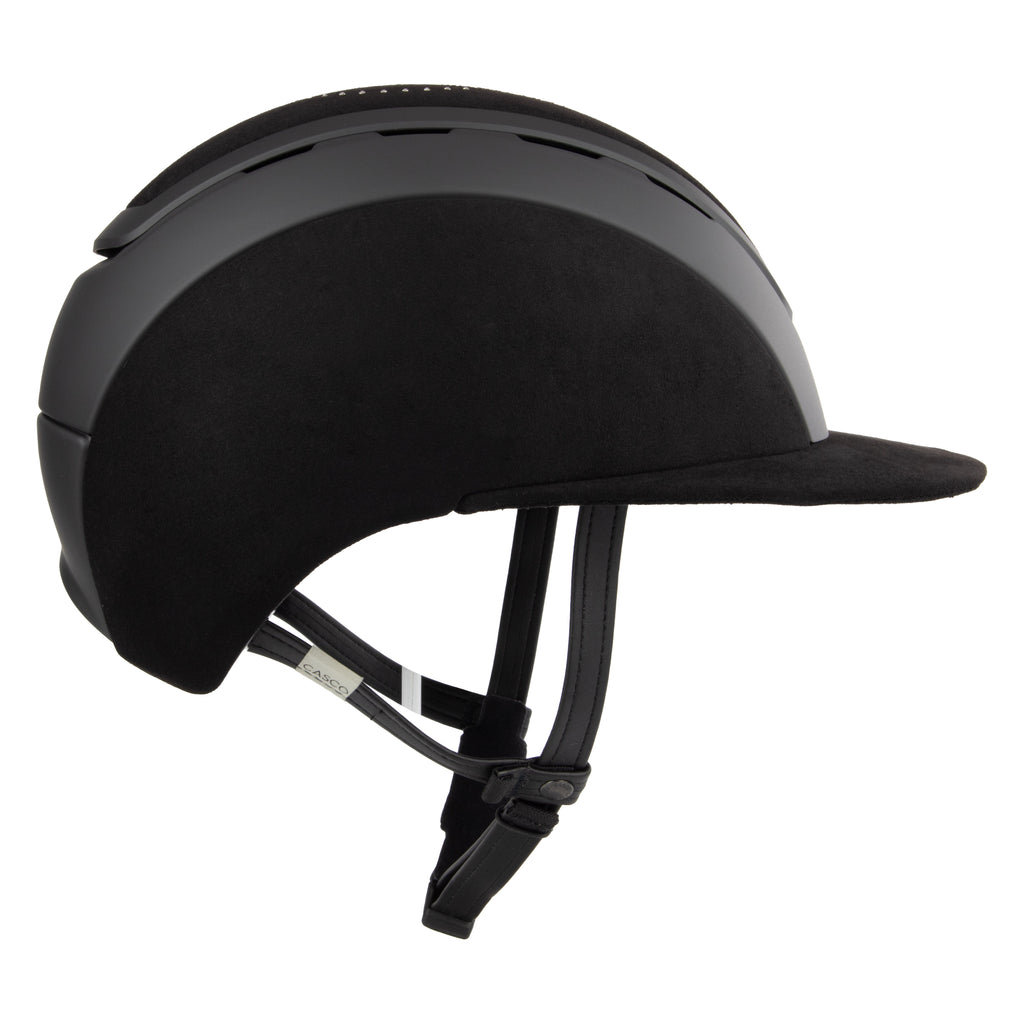 Side view of A black Casco equestrian riding helmet with a matching visor, matte finish, brushed nubuck leather with Swarovski crystals and adjustable chin strap, shown on a solid white background.