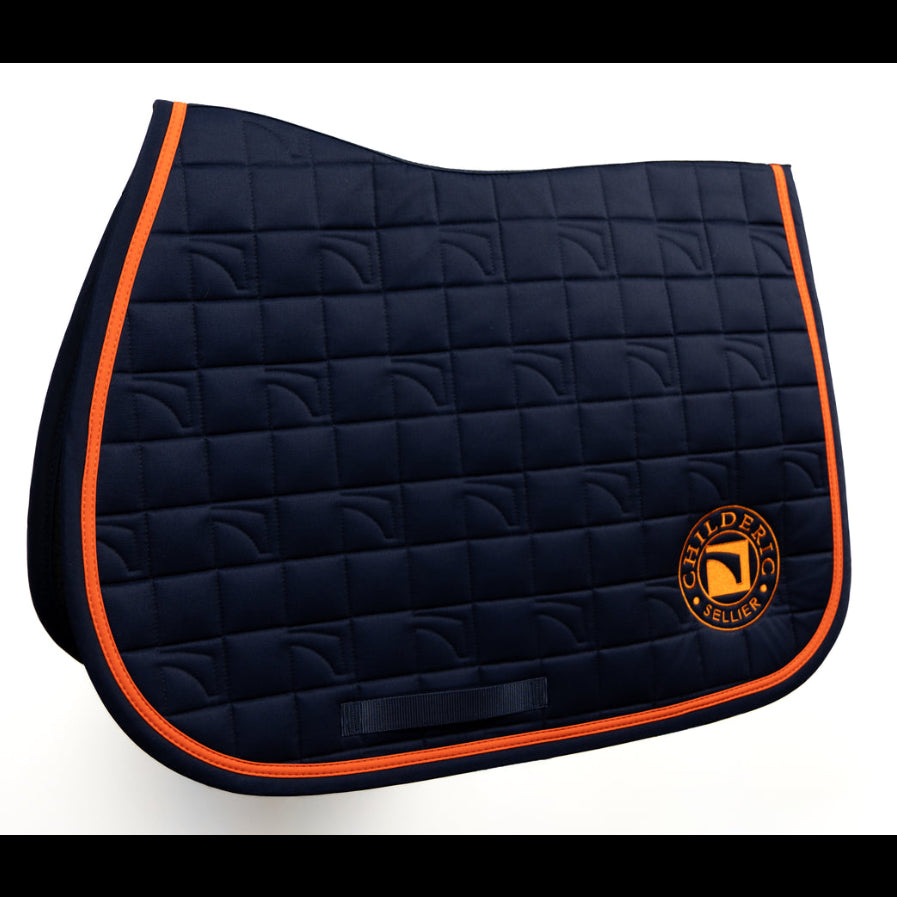 A navy blue quilted horse Childeric saddle pad with bright orange piping and a circular Childeric logo patch on the lower right, shown on a clean white background.