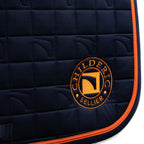Close-up of a Childeric black quilted equestrian saddle pad with vibrant orange piping and a circular embroidered Childeric logo on the lower right, set against a plain white background.